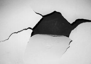 white painted wall with holes and peeling paint.
