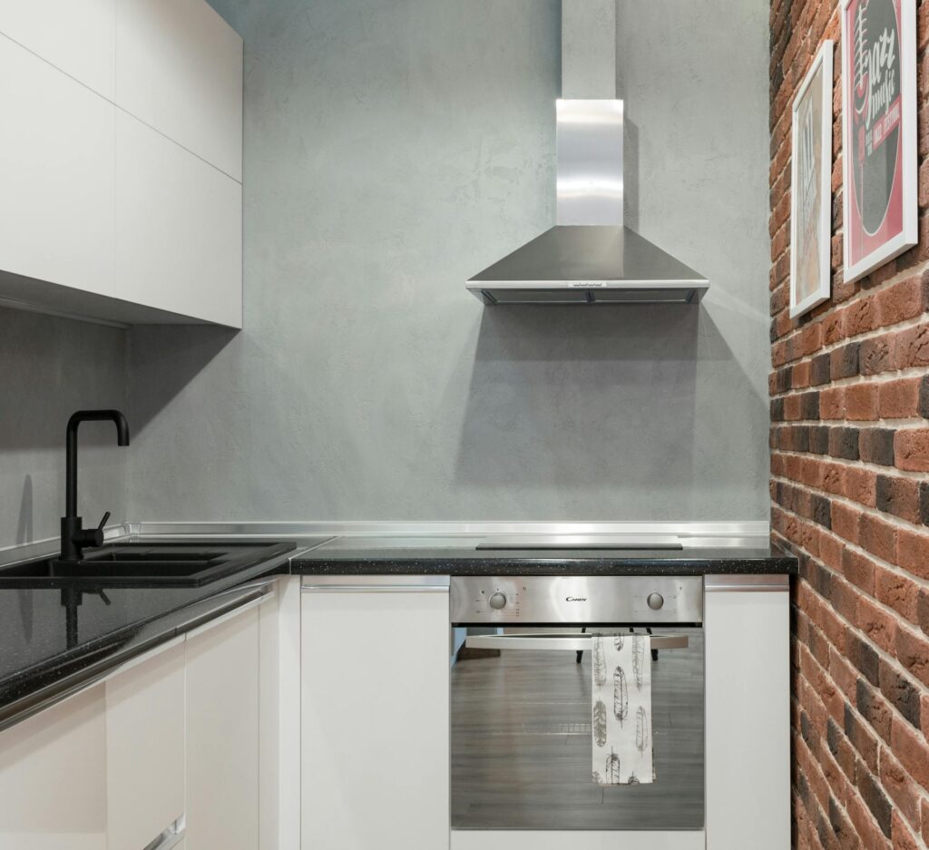 How to Clean a Range Hood Filter Contemporary kitchen interior with stainless steel appliances and brick wall.