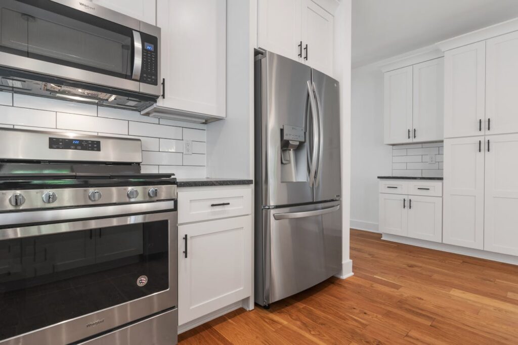 How to Clean Under Large Appliances Spacious modern kitchen featuring stainless steel appliances and white cabinetry.