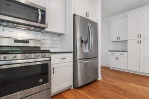How to Clean Under Large Appliances Spacious modern kitchen featuring stainless steel appliances and white cabinetry.