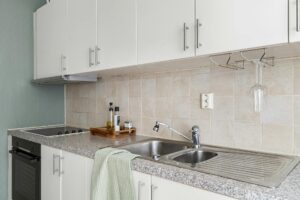 Sleek modern kitchen with granite countertops, stainless steel sink, and white cabinets.