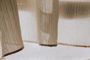 Close-up of sheer fabric with sunlight creating delicate shadows and textures, perfect for textile design.