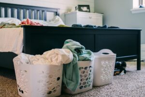 How to Keep Laundry from Piling Up A cozy bedroom scene featuring laundry baskets filled with clothing, placed on a carpeted floor.