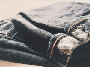 How to Prevent Lint Buildup on Clothes Detailed view of folded denim jeans in soft, warm lighting.