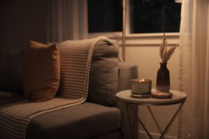 How to Shut Down Your Home at Night A warm and inviting living room scene featuring a lit candle, sofa, and decorative elements.