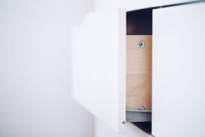 How to Childproof a Home Close-up of an open white drawer revealing a wooden interior and screws in a minimalist design.