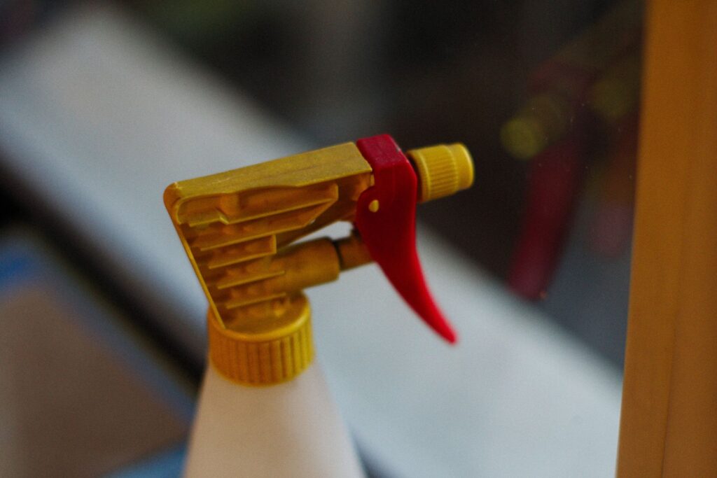 Detailed view of a yellow and red spray bottle nozzle in focus.