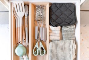 How to Organize Kitchen Drawers Efficiently Neatly arranged kitchen tools and textiles in a drawer, showcasing an organized culinary space.