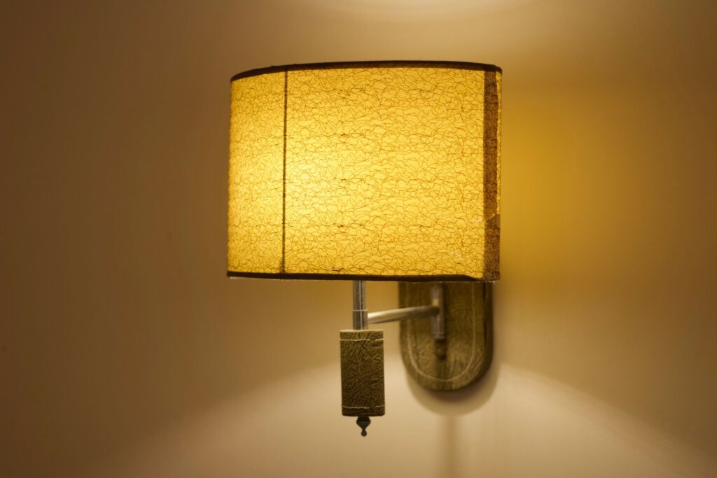 Soft yellow wall lamp with a textured shade casts a warm glow indoors.