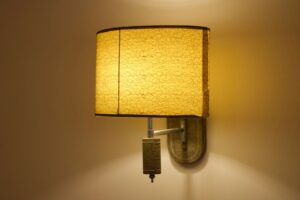 Soft yellow wall lamp with a textured shade casts a warm glow indoors.