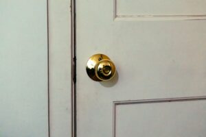 How to Stop a Door from Sticking White door featuring a shiny brass knob, ideal for home interior design themes.